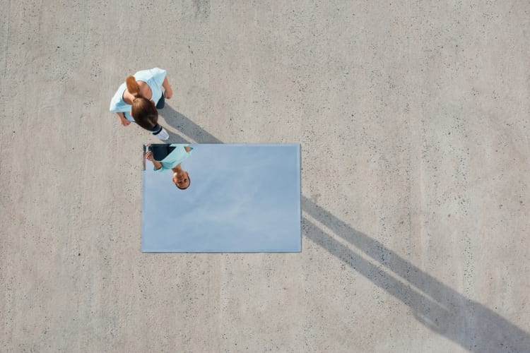 Woman standing above mirror and reflection outdoors